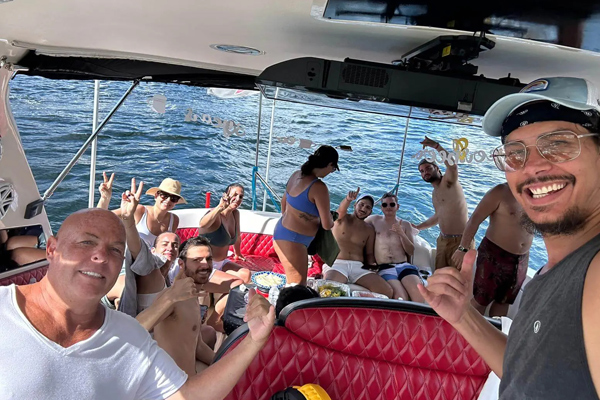 a man sitting on a boat with a bunch of food. featuring South Florida boating and tiki bar experiences in Fort Lauderdale